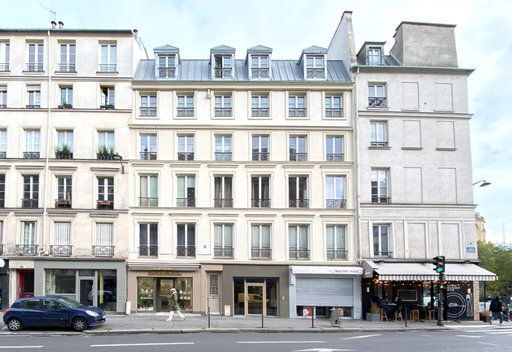 Façade rénovée après surélévation à Paris, avec ravalement, nouvelles menuiseries et lucarnes en toiture.